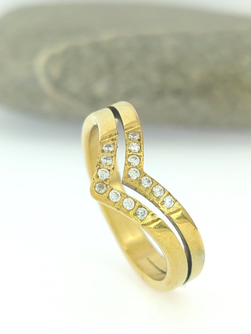 Gold ring with embedded diamonds on a neutral background