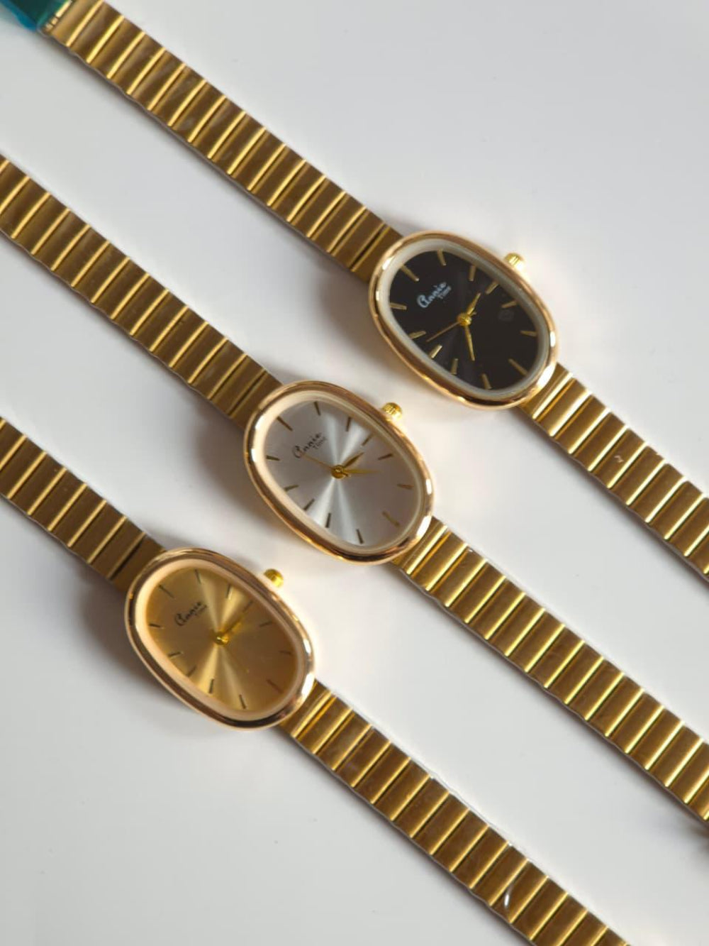 Three gold wristwatches with different face designs on a white background